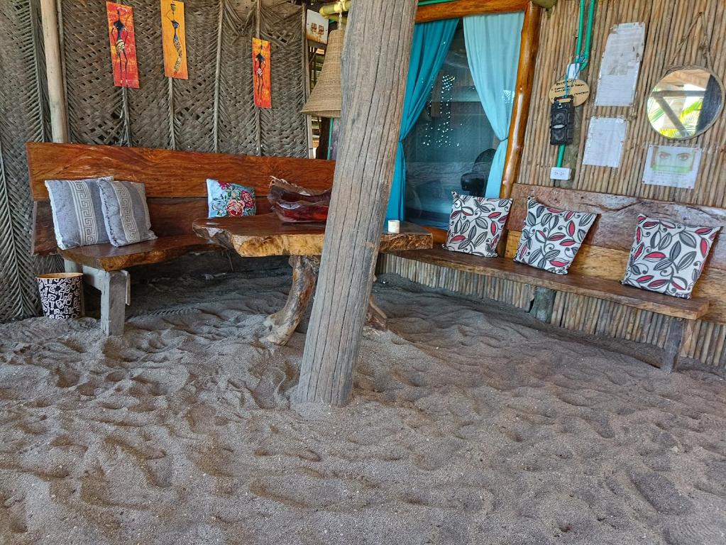 un banc en bois assis dans le sable avec des oreillers dans l'établissement Bob Marley Beach, à Guachaca