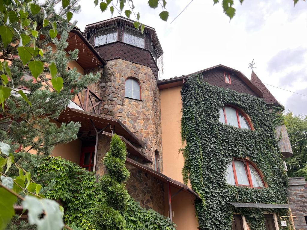 a building covered in ivy with a tower at Polyanskiy Zamok in Polyana