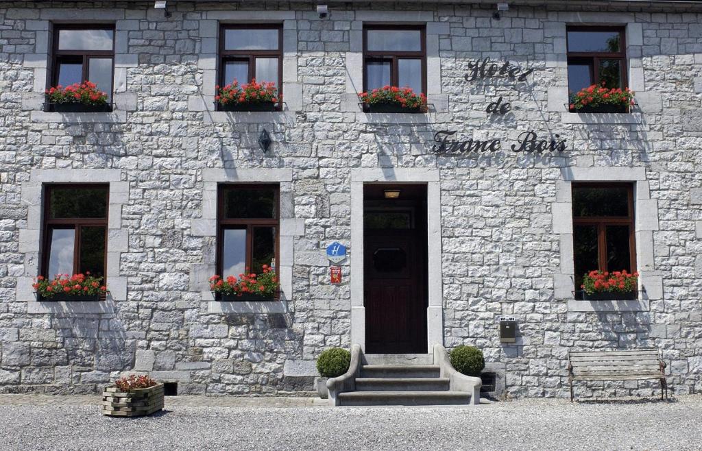 un edificio in pietra con una porta e fiori di Hotel De Franc Bois a Chimay