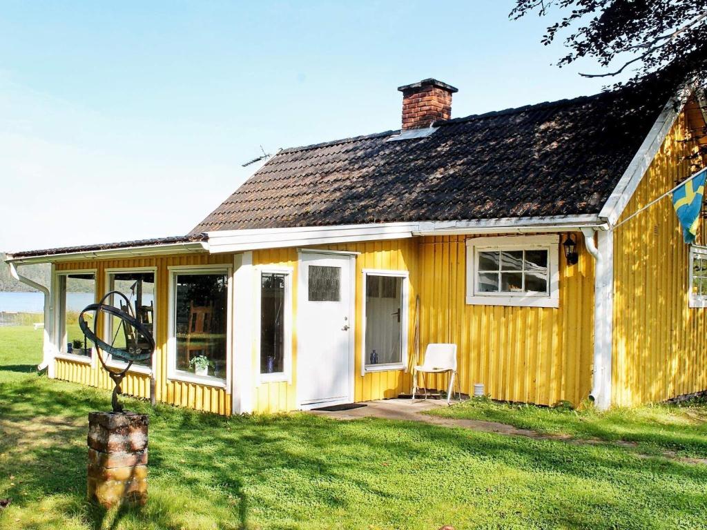 a yellow house with a white door and a yard at 4 person holiday home in LERDALA-By Traum in Lerdala