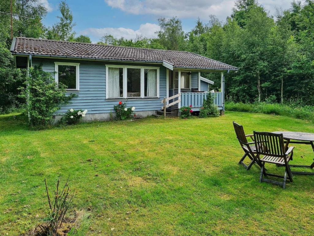 uma casa azul com uma mesa e um banco num quintal em 4 person holiday home in Heberg em Heberg