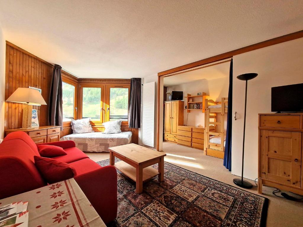- un salon avec un canapé rouge et un lit dans l'établissement Studio confortable à La Daille, ski-in ski-out, balcon sud, 4 pers., proche commerces et navettes - FR-1-518-136, à Val dʼIsère