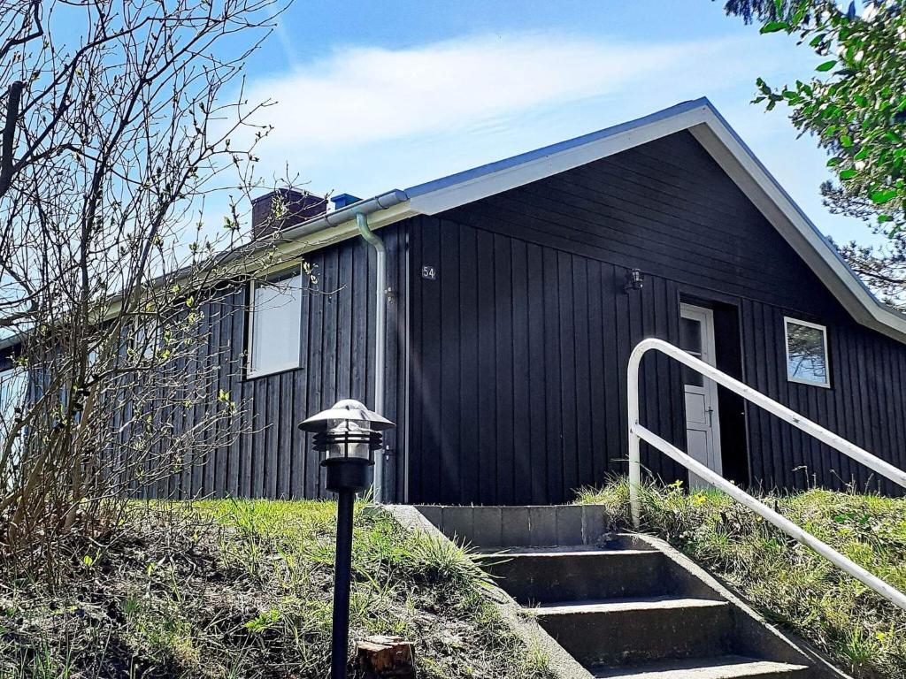 een zwart huis met een trap daarheen bij 5 person holiday home in R m in Kongsmark