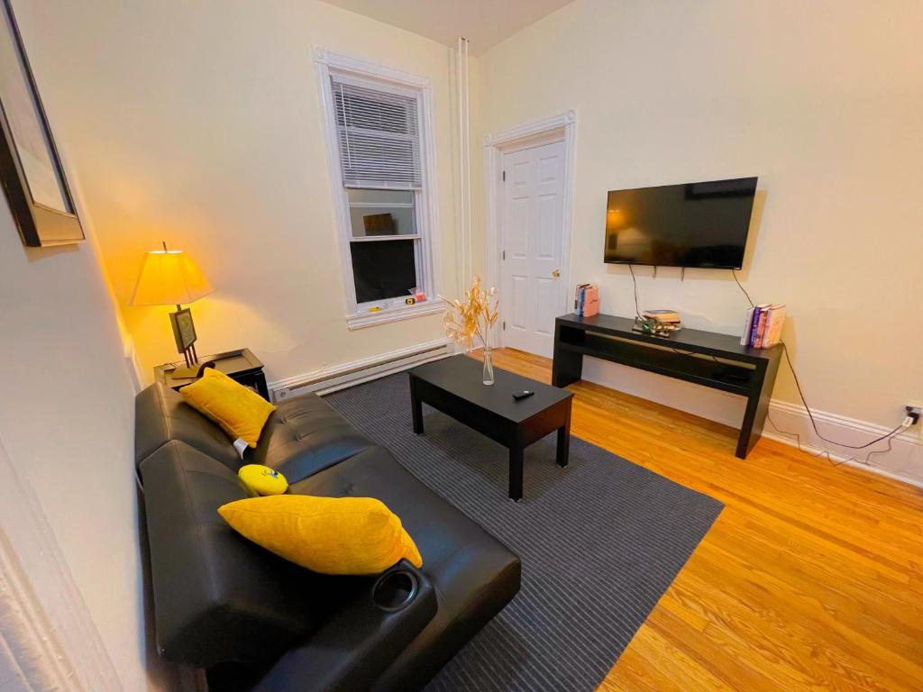 a living room with a black leather couch and a television at Home sweet home in the heart of Wilmington. in Wilmington