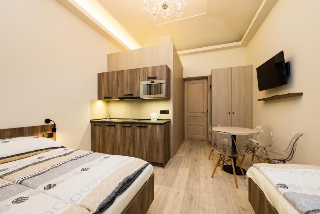 a bedroom with two beds and a kitchen with a desk at Ostrovni Astra Apartment in Prague