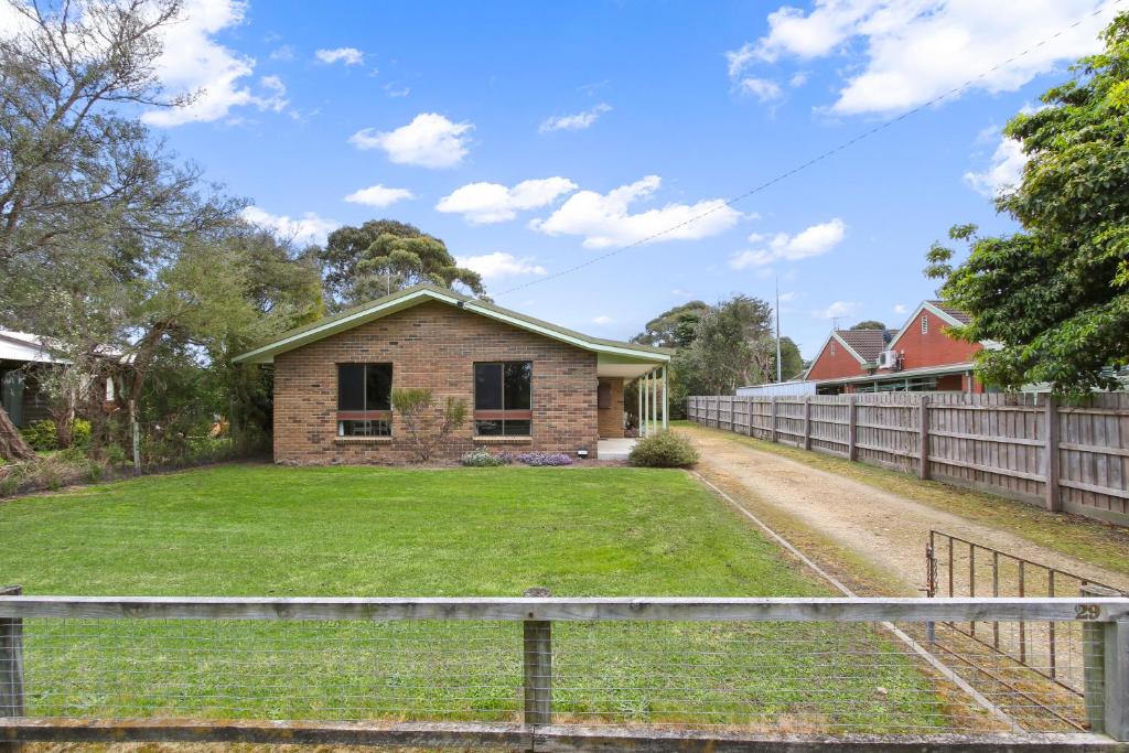 a brick house in a yard with a fence at Deppelers in Lakes Entrance