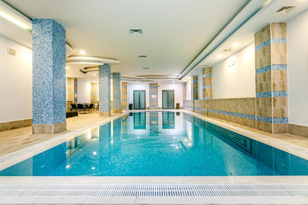 una gran piscina con azulejos azules en las paredes en İsr Baku Hotel apartment with a pool, en Baku