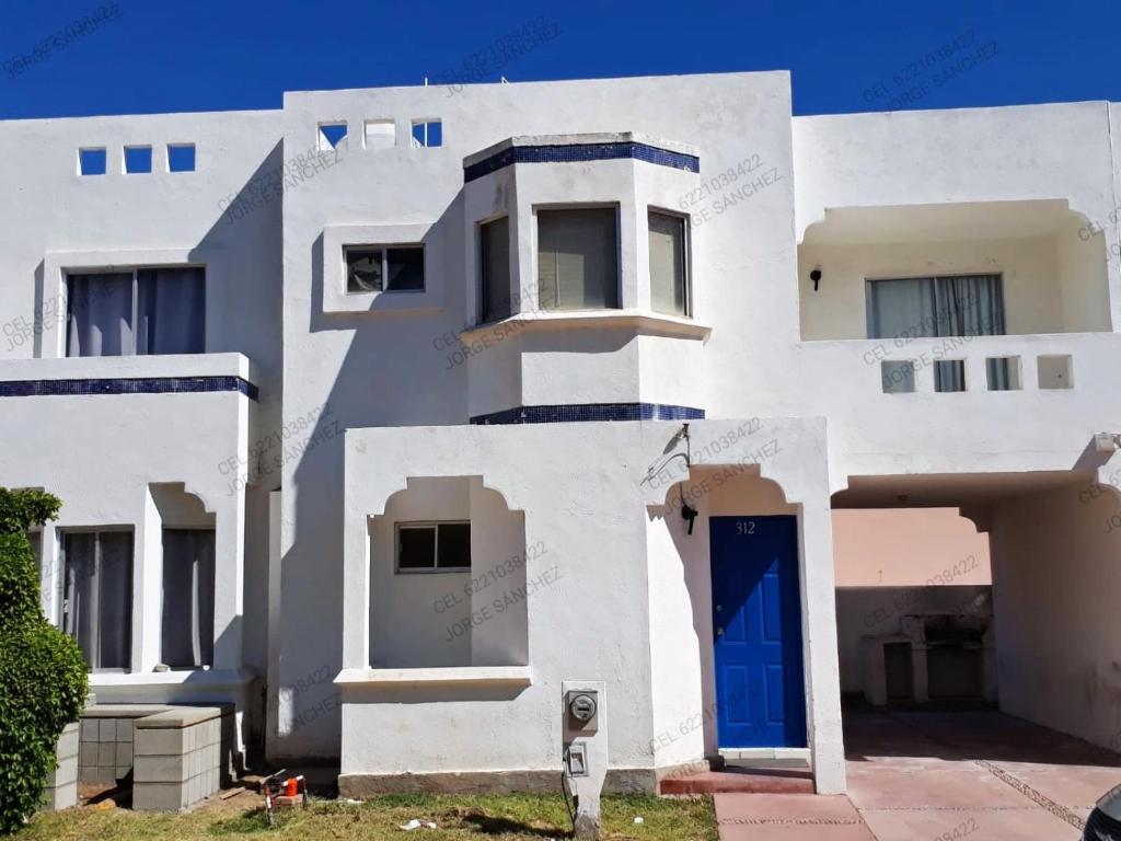una casa blanca con una puerta azul delante de ella en Condominio 312 Loma Bonita, en San Carlos