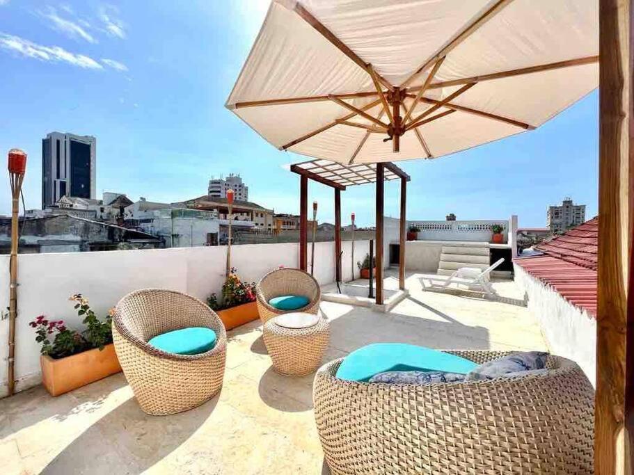 a patio with chairs and an umbrella on a roof at 5br COZY HOUSE ROOFTOP POOL AC OLD CITY in Cartagena de Indias