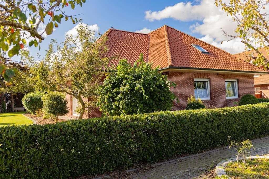 una casa de ladrillo con un seto delante de ella en Schönes & gemütliches Ferienhaus nahe der Nordsee en Schortens