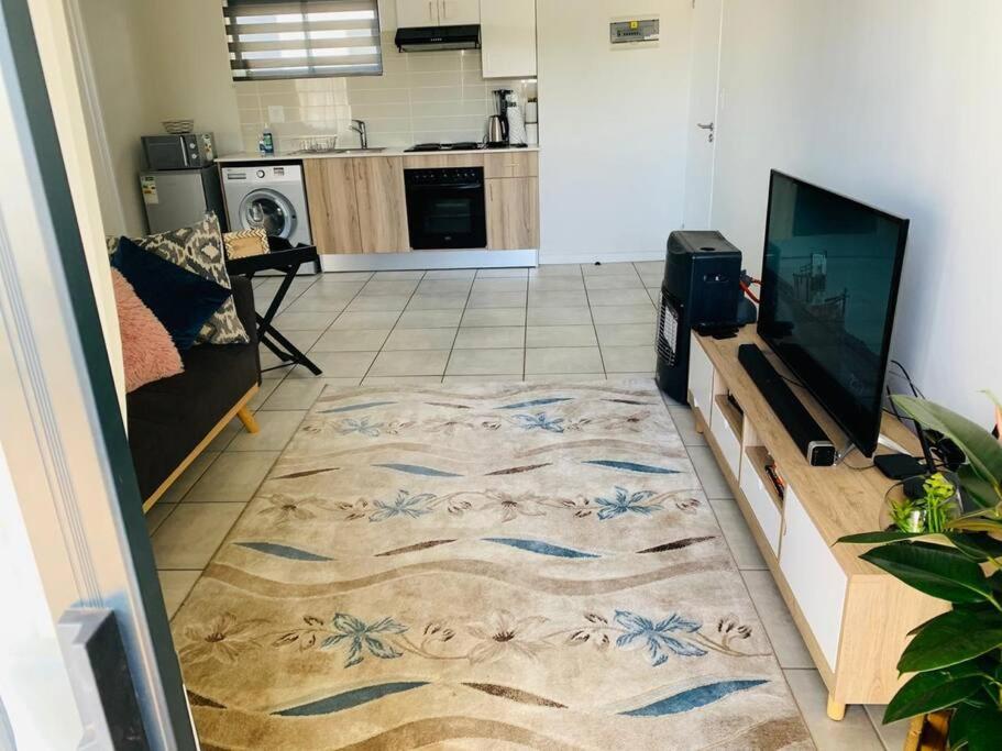 a living room with a television and a rug at The Parks Airport Apartment in Boksburg