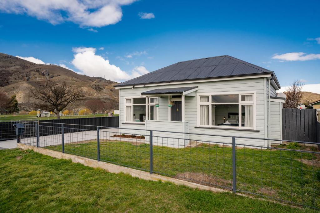 a white house with a black roof at Lake Dunstan Cottage - Cromwell Holiday Home in Cromwell