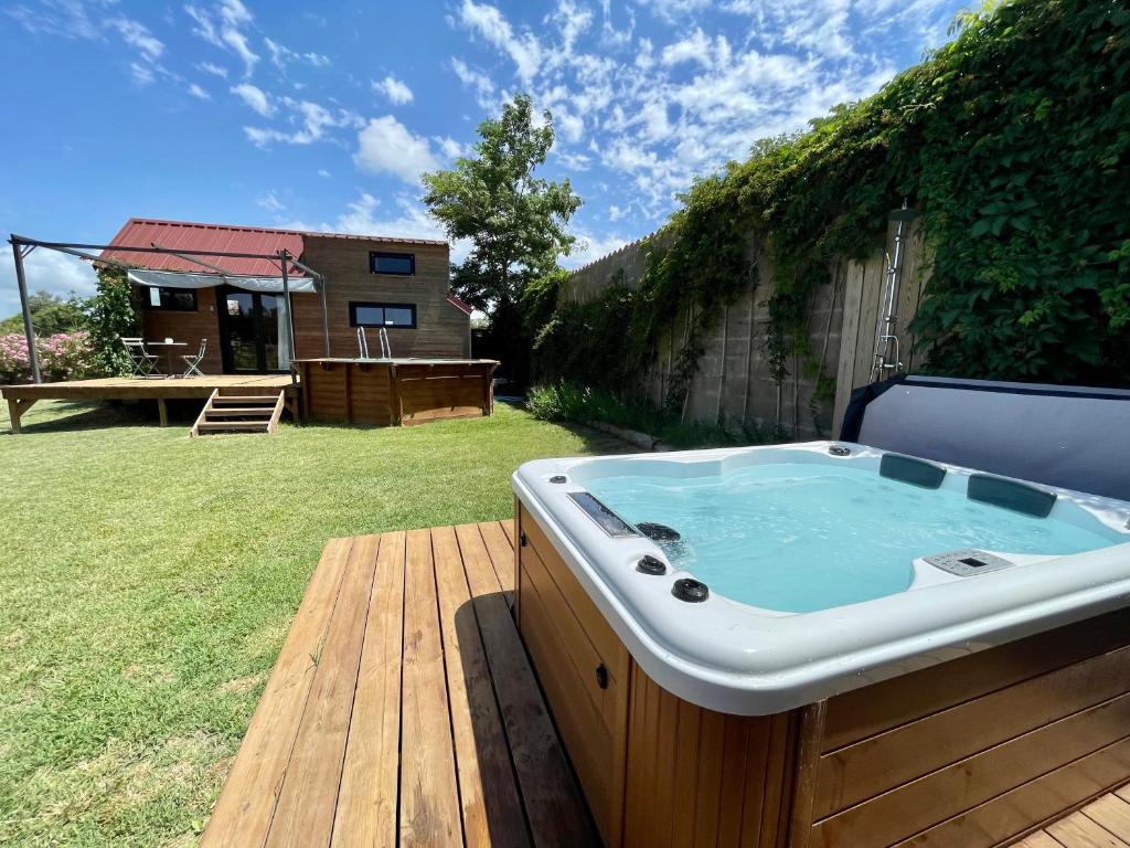 エーグ・モルトにあるmyinsolite - Tiny-house, jacuzzi, brasero, piscineの庭園のデッキに座ってホットタブを利用できます。