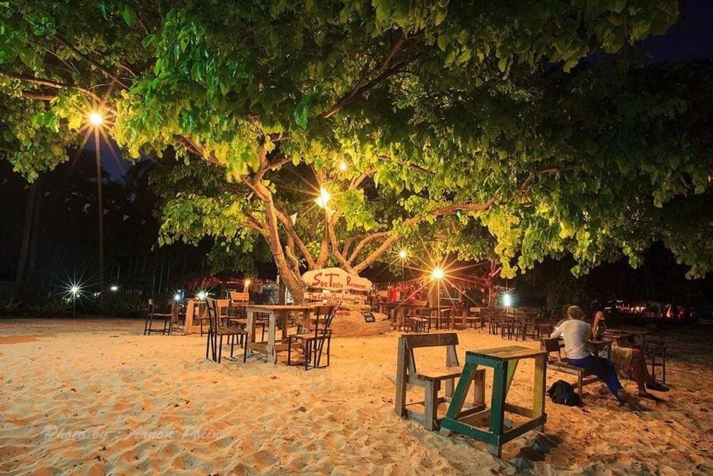 een groep tafels en stoelen onder een boom bij Koh Ngai Sea Open Resort in Ko Ngai