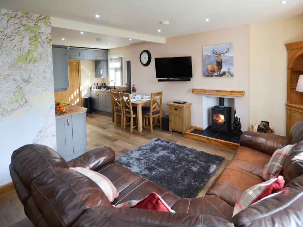 a living room with a leather couch and a fireplace at Uplands in Dalbeattie