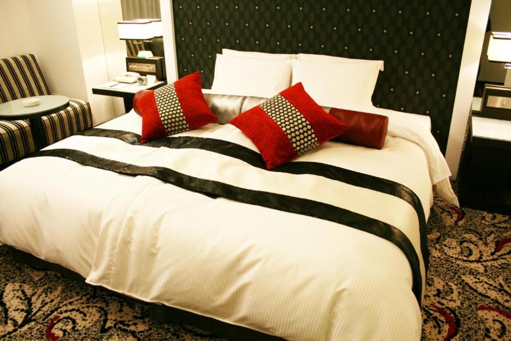 a large bed with red and white pillows on it at New Otani Inn Tokyo in Tokyo