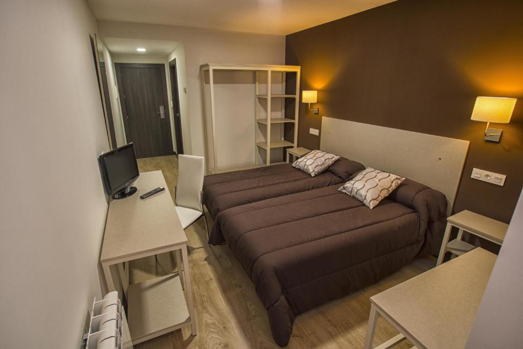アランダ・デ・ドゥエロにあるホステル エルビラのベッドとデスクが備わる小さな客室です。