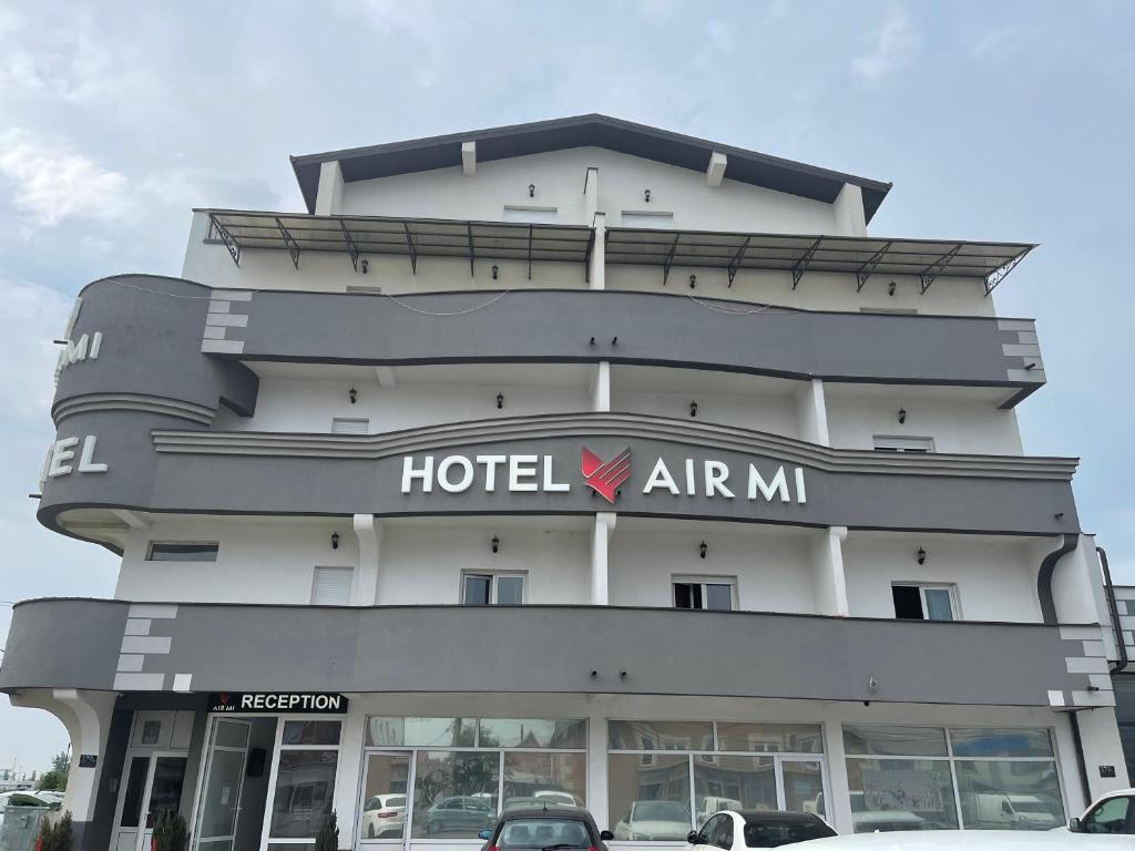 AirMi hotel في Surčin: مبنى فندق ارماراما فيه سيارات تقف امامه