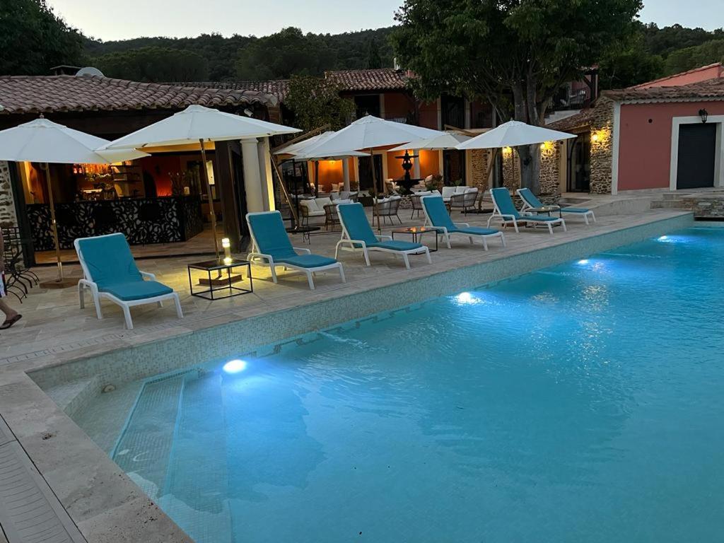 a swimming pool with blue chairs and umbrellas at Auberge du dom in Bormes-les-Mimosas