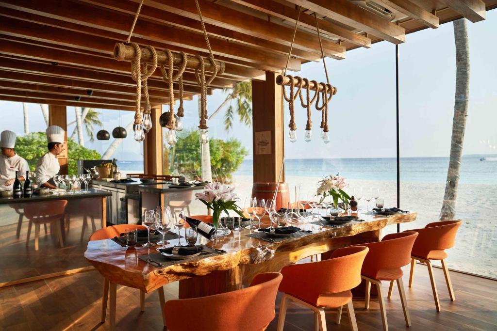 a dining room with a table and chairs and the ocean at Siyam World Maldives - 24-Hour Premium All-inclusive with Free Transfer in Dhigurah