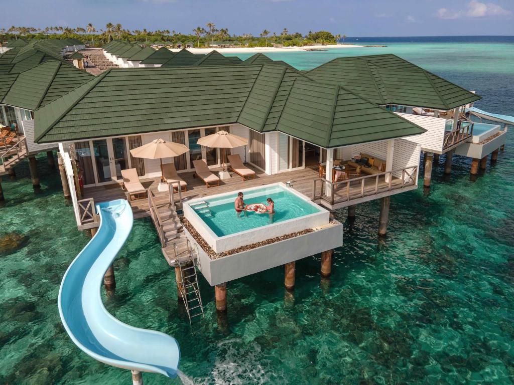 een huis aan het water met een zwembad en een glijbaan bij Siyam World Maldives - 24-Hour Premium All-inclusive with Free Transfer in Dhigurah