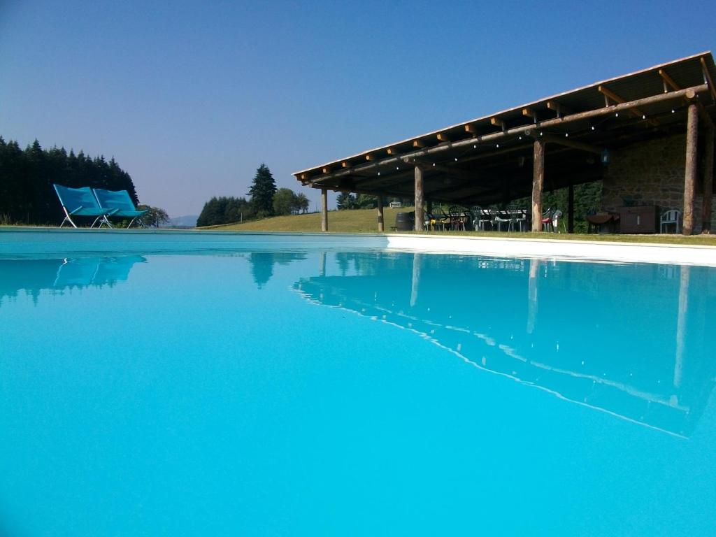 une grande piscine d'eau bleue avec un pavillon dans l'établissement Le domaine des Terres, à Saint-Appolinaire