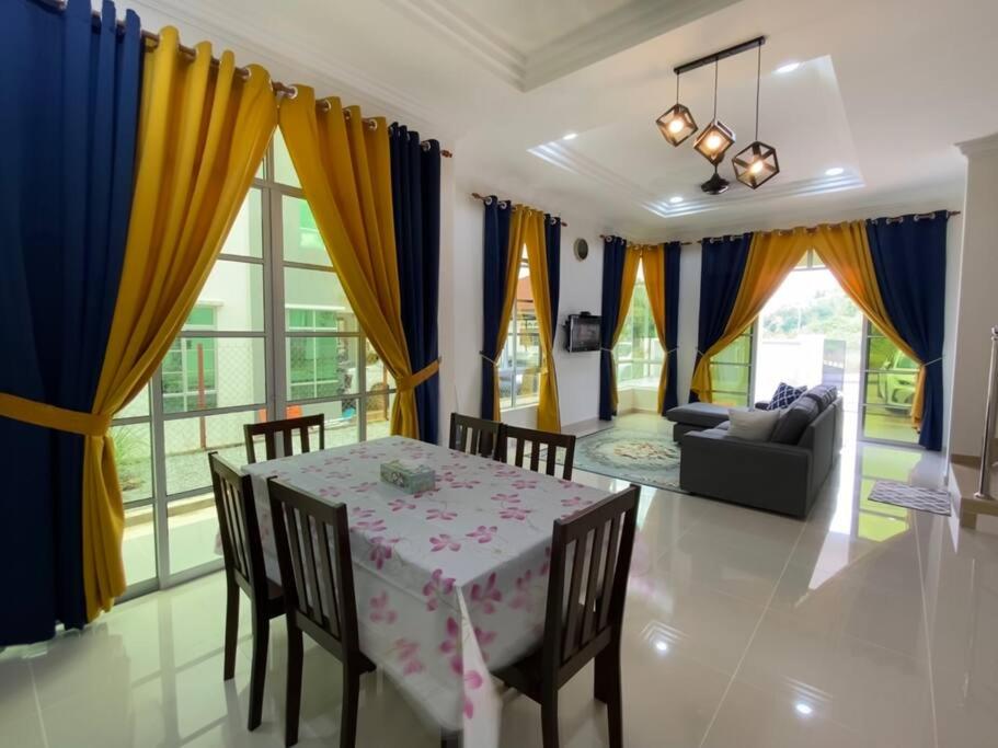 uma sala de jantar com uma mesa e cadeiras e um sofá em homestay kubang ikan chendering 5minit ke pantai em Kuala Terengganu