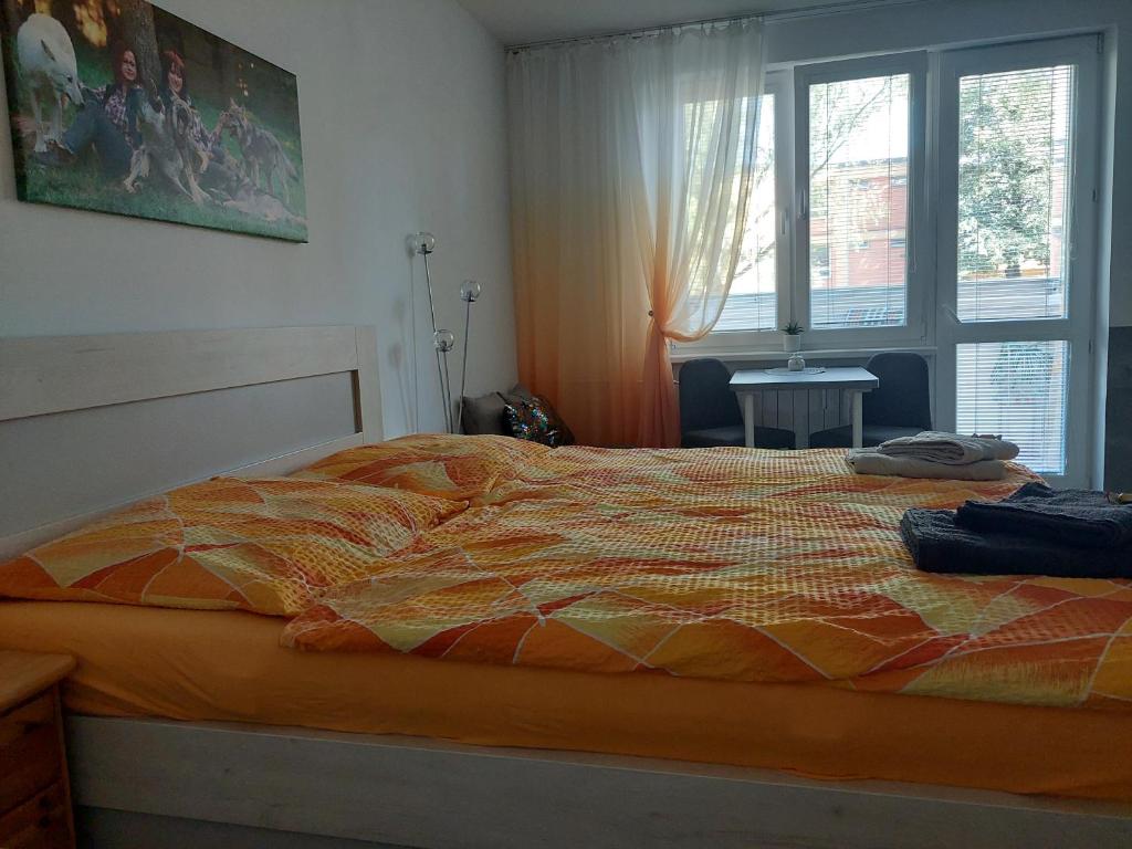 1 dormitorio con 1 cama con edredón de naranja y ventana en Garsonka Ostrava, en Ostrava