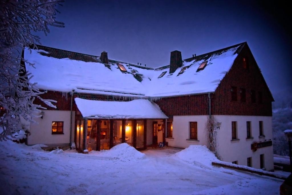 una casa está cubierta de nieve por la noche en Am Roten Hammer I Gasthof und Pension, en Kurort Oberwiesenthal