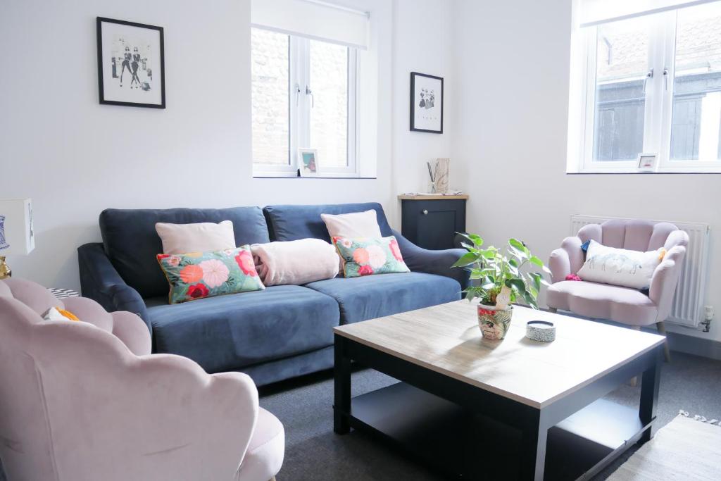 ein Wohnzimmer mit einem blauen Sofa und 2 Stühlen in der Unterkunft 2 bed luxury duplex apartment in heart of Holt in Holt