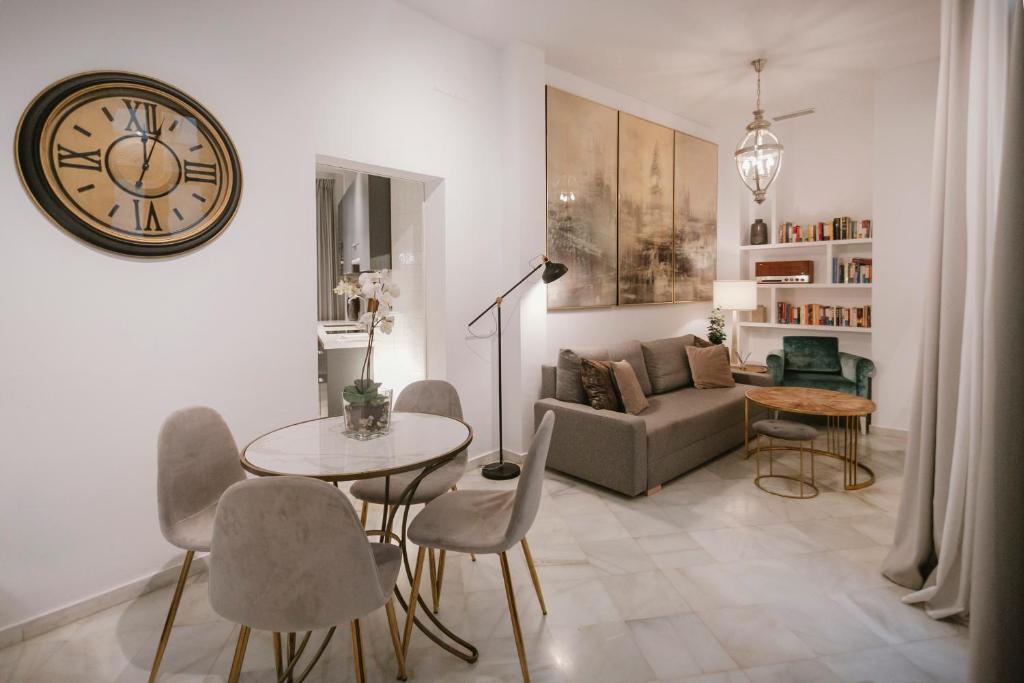 sala de estar con mesa y reloj en la pared en Precioso apartamento con patio en La Alameda, en Sevilla