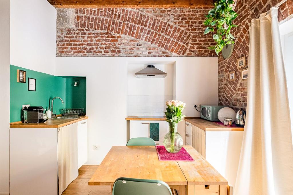 een keuken met een houten tafel en een bakstenen muur bij Ripa Apartments Milano - Ripa 57 in Milaan