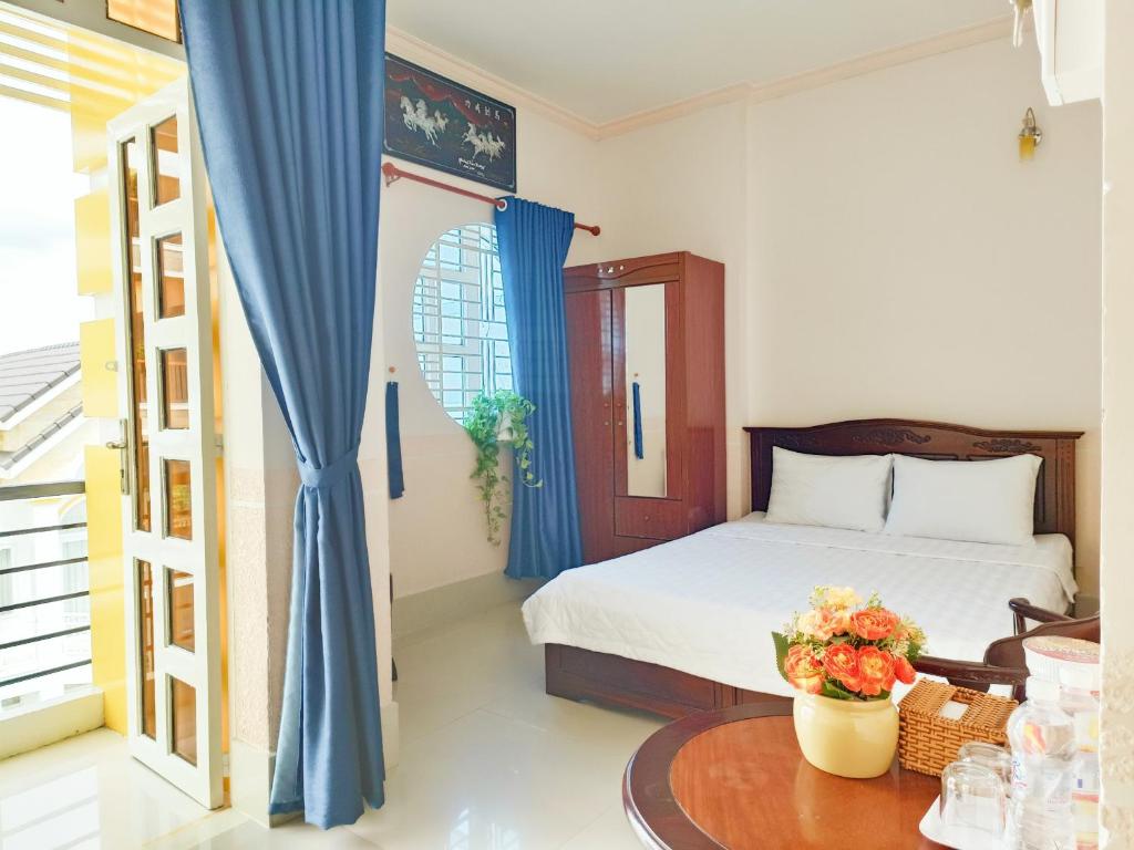 1 dormitorio con 1 cama con cortinas azules y mesa en NAMA HOTEL - Ninh Kieu Center en Can Tho
