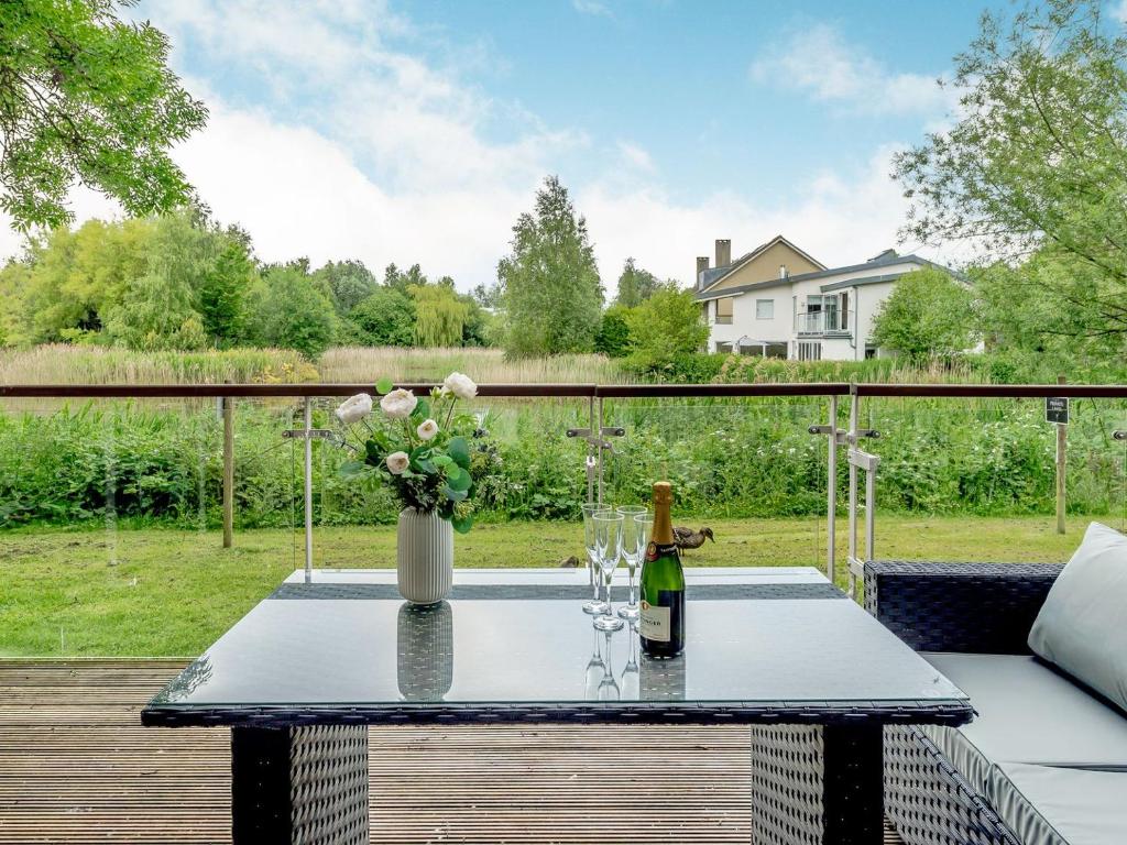a table with a bottle of wine and flowers on a deck at Plovers Nest At Lower Mill in Somerford Keynes
