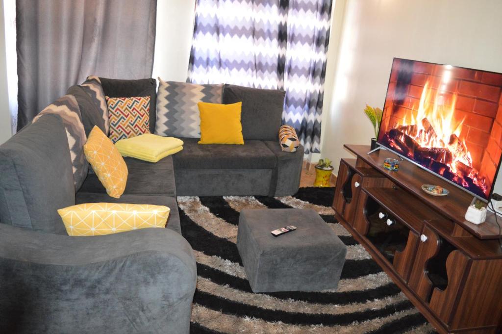 ein Wohnzimmer mit einem Sofa und einem TV in der Unterkunft Modern Ruiru double deluxe, Thika Road in Ruiru