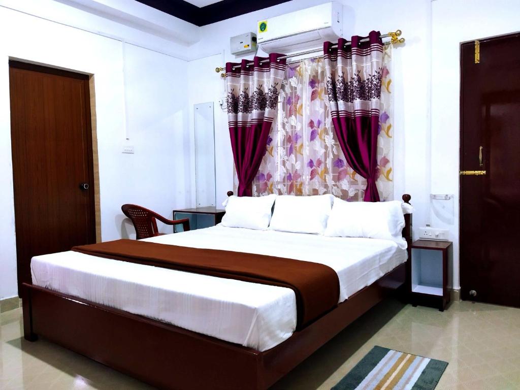 1 dormitorio con 1 cama grande y cortinas moradas en Continental Homestay en Port Blair