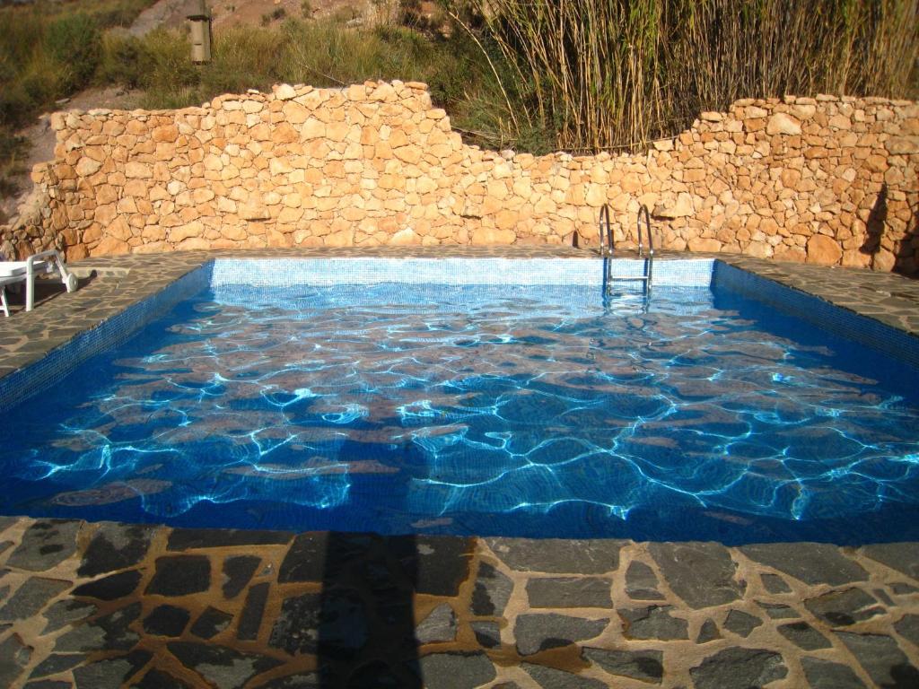 una piscina con agua azul frente a una pared de piedra en Finca-Privatpool-sehr ruhige Lage-Alleinnutzung-ideal für Familien, en Níjar