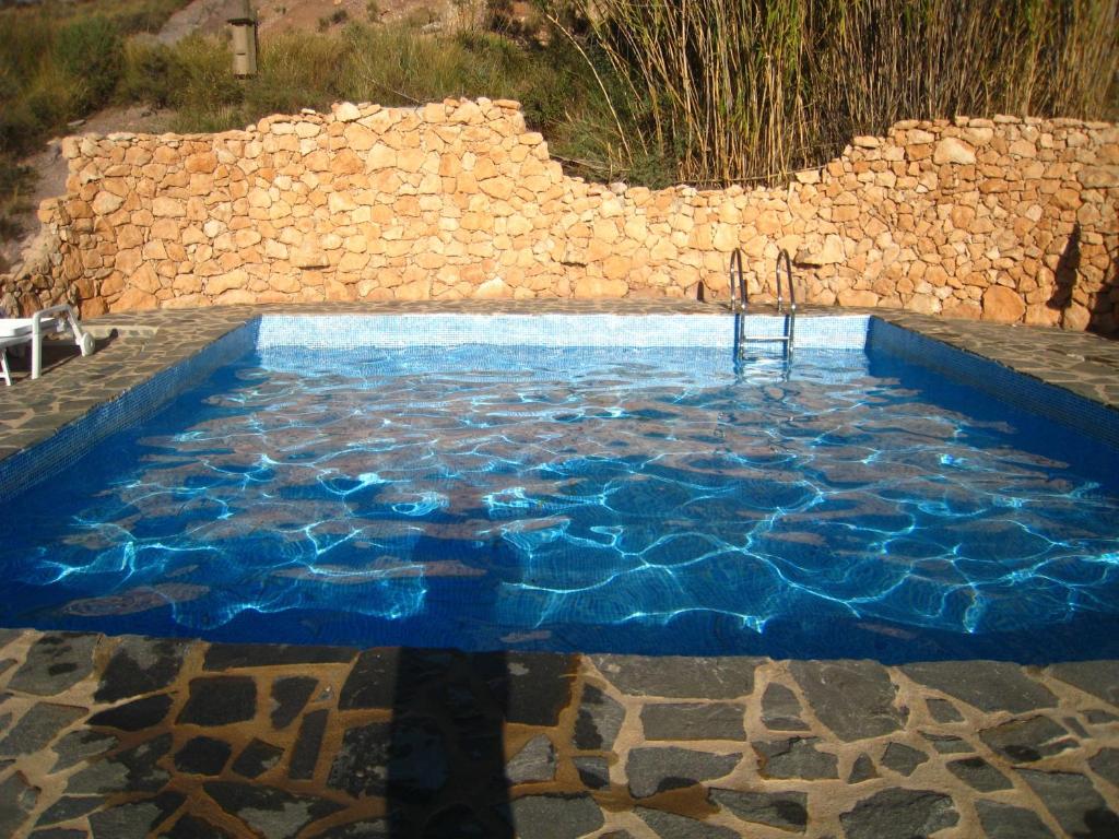 a pool with blue water in front of a stone wall at Finca-Privatpool-sehr ruhige Lage-Alleinnutzung-ideal für Familien in Níjar