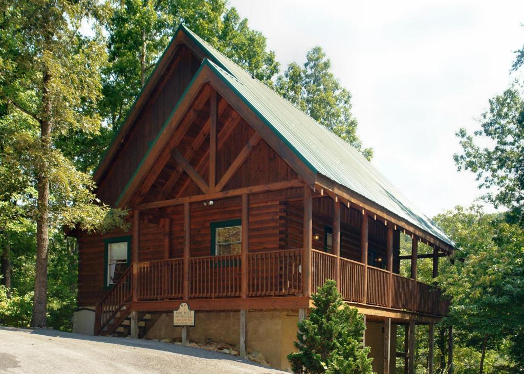 eine Blockhütte im Wald mit einer Veranda in der Unterkunft Buddy Bear #249 in Pigeon Forge