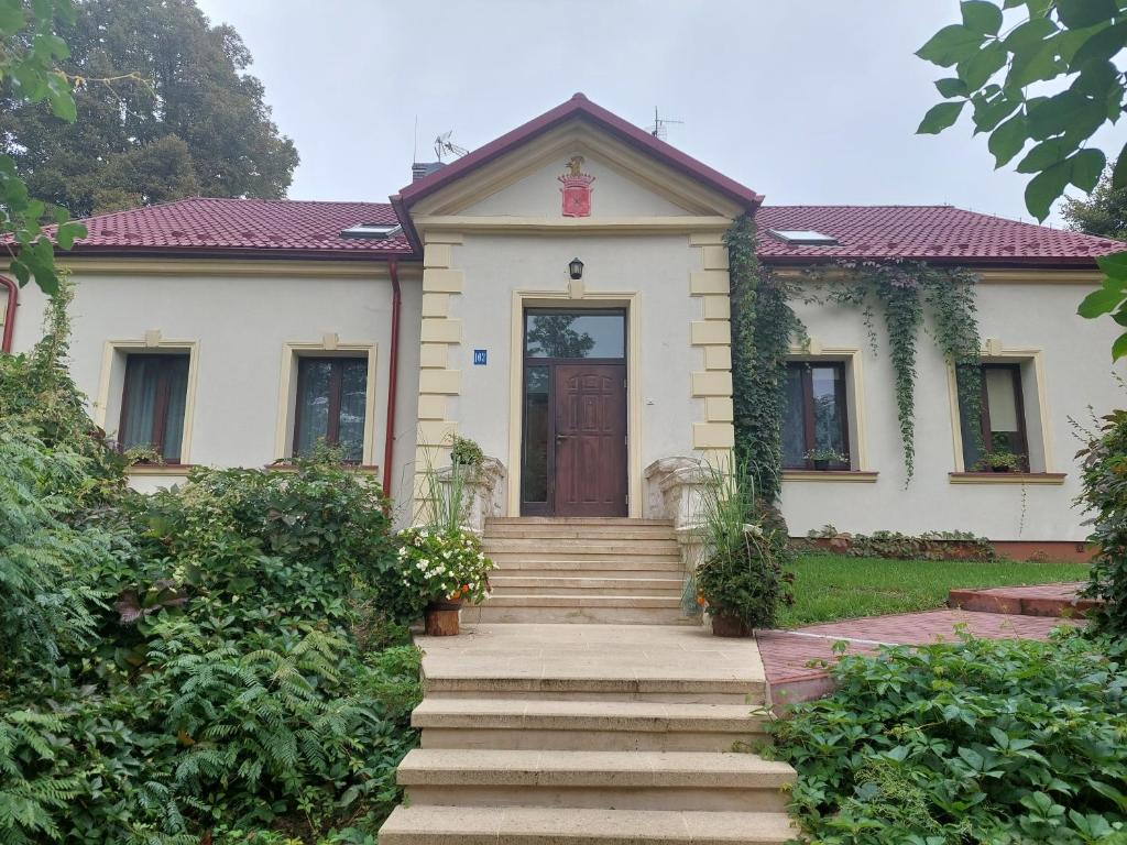 a white house with a brown door and stairs at Leśniczówka Hamernia 