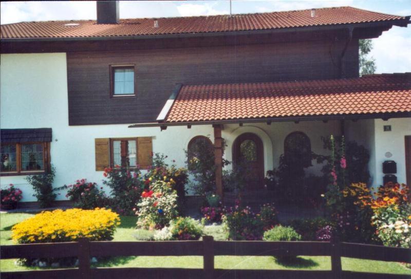 una casa con una valla y flores delante de ella en Ferienwohnung Edmeier, en Bernau am Chiemsee