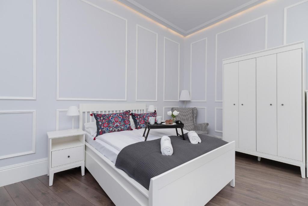 a white bedroom with a bed and a dresser at Perła Starego Miasta Kamienica Czapskich by Renters in Krakow
