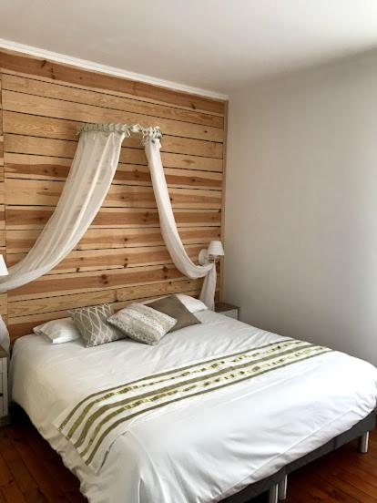 a bedroom with a white bed with a wooden headboard at L'hostellerie de Sèvremont in Saint-Michel-Mont-Mercure