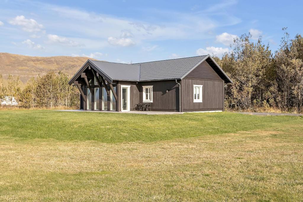 ein kleines Haus auf einem Feld mit einem Rasenplatz in der Unterkunft Luxury Country Cottage with 360° Mountain View in Brautarholt