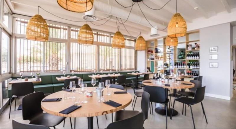 a restaurant with tables and chairs and windows at Hôtel Café Miramar in Le Grau-du-Roi