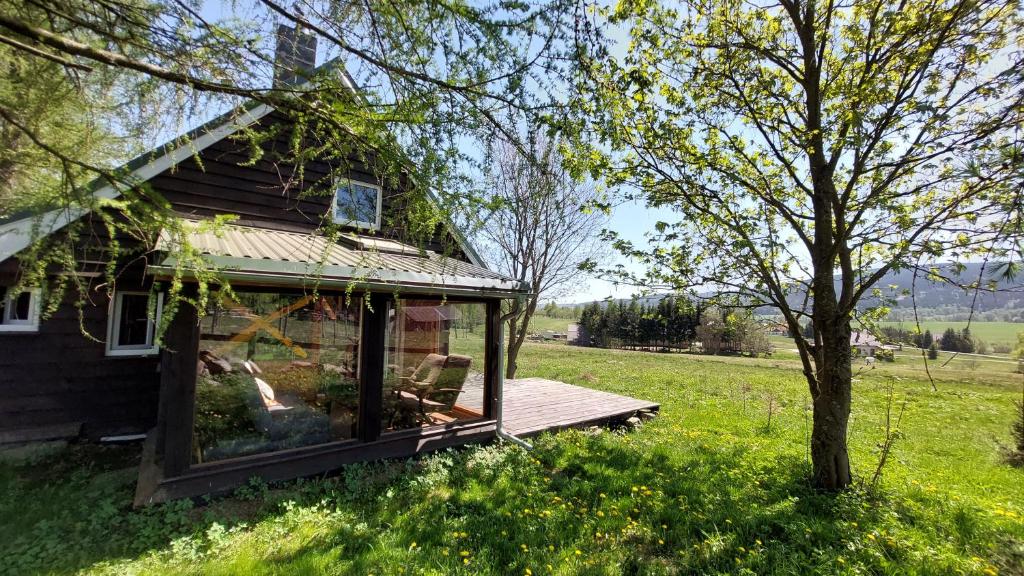 Domek z widokiem na góry Lasówka في بستشستا كوودزكا: منزل صغير مع سطح في ميدان