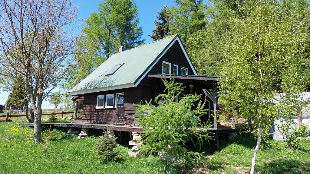 uma cabana de madeira com um telhado verde numa ponte em Domek z widokiem na góry Lasówka em Bystrzyca Kłodzka