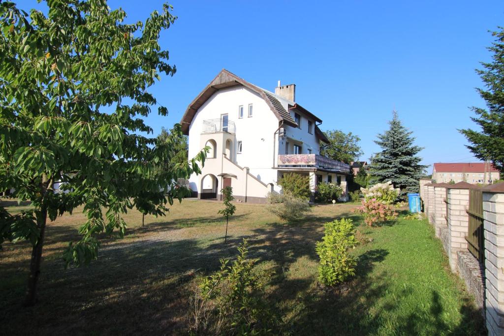 a large white house on a grassy field at Villa Lounika in Warnowo