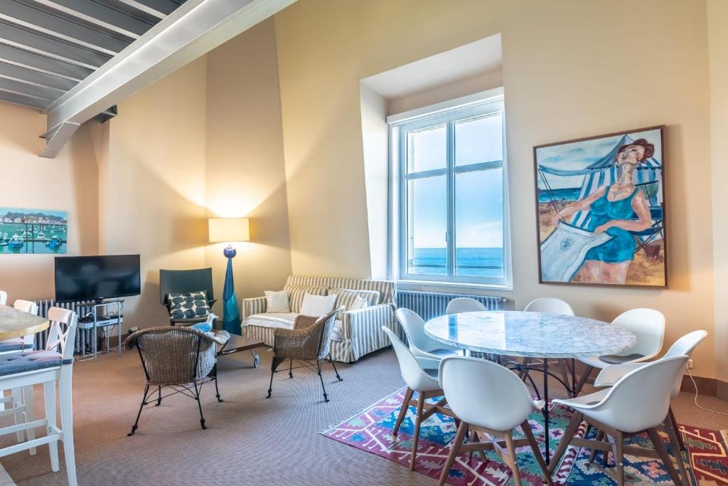 un salon avec une table et des chaises et une fenêtre dans l'établissement SUN KEYWEEK Duplex Breathtaking view of the Ocean and Palace Gardens, à Biarritz