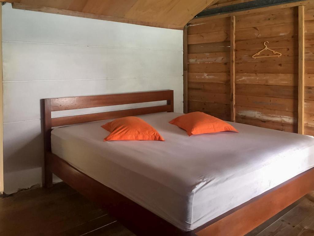 a bed with two orange pillows in a room at Olala Bungalows And Restaurant Mitra RedDoorz in Banda Aceh